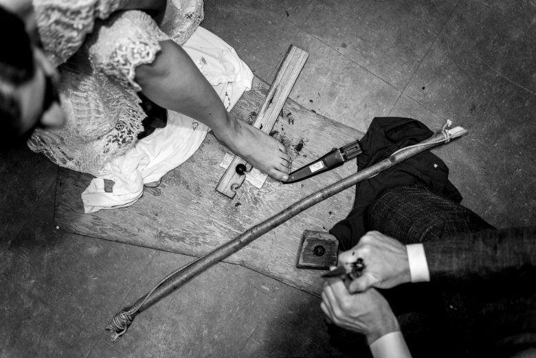 Birds eye view of bride and groom building fire by rubbing sticks together